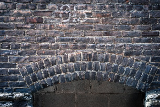 The side of a brick building with some numbers written on it.